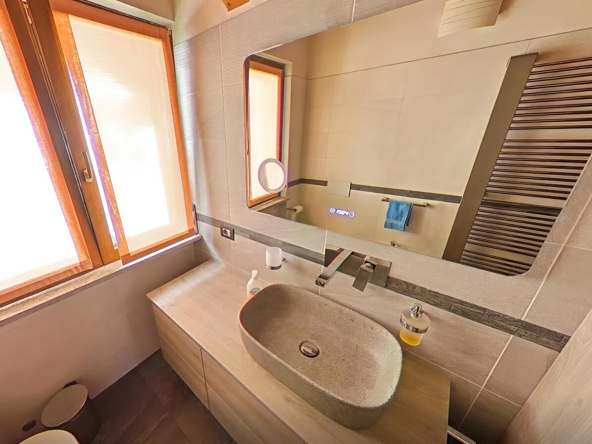Bagno mansarda in montagna con lavabo in pietra e finiture moderne, virtual tour immobiliare