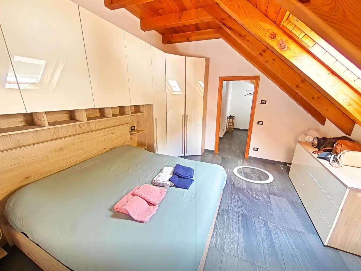 Camera matrimoniale in mansarda con tetto inclinato e arredi su misura, virtual tour casa montagna